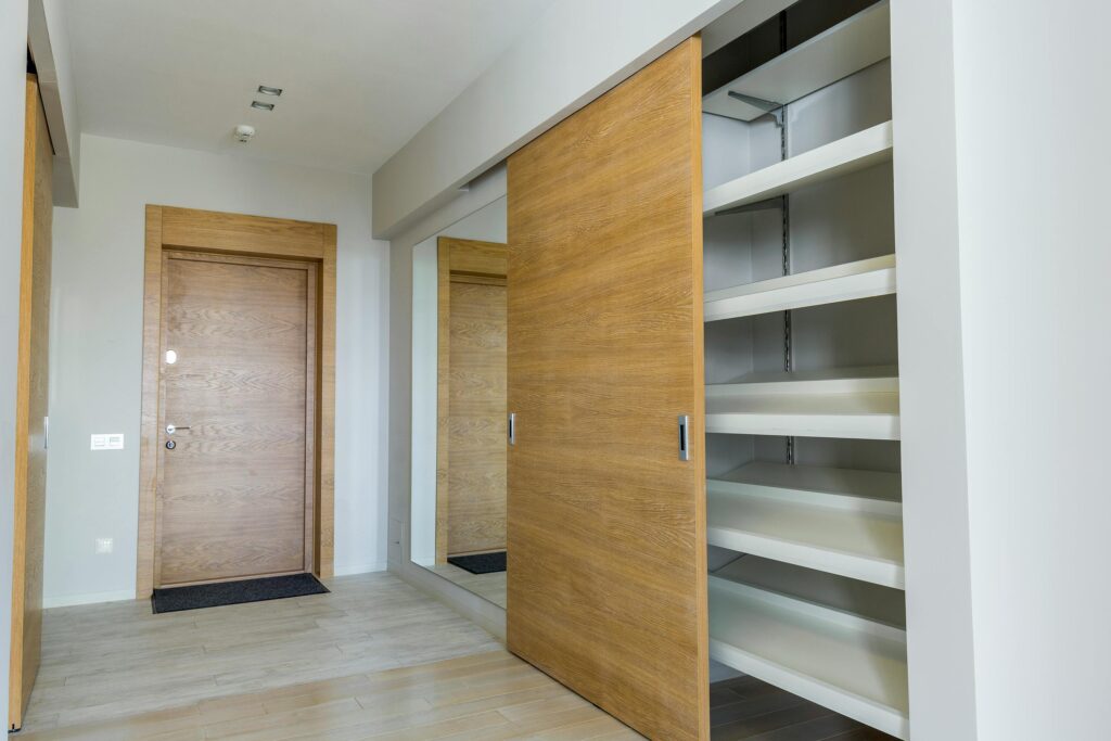 Elegant modern walk-in closet with wooden sliding door and empty shelves in a sleek minimalist style.