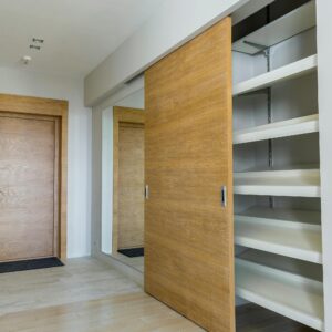 Elegant modern walk-in closet with wooden sliding door and empty shelves in a sleek minimalist style.